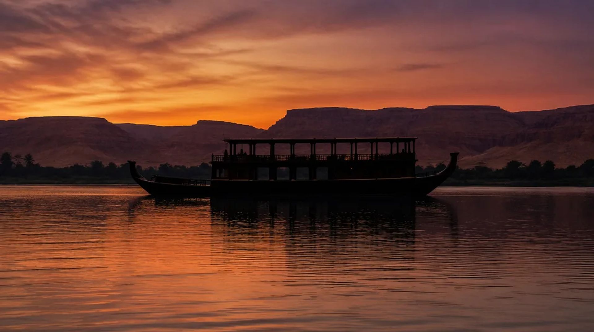 5-star Nile cruise ship sailing between Luxor and Aswan at golden hour