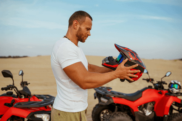 Man holding a motorcycle helmet outdoors.