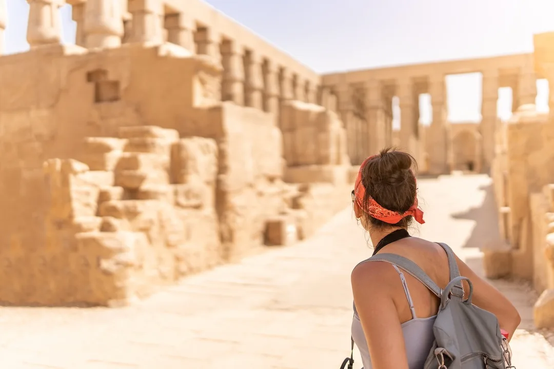 Woman exploring ancient sunlit temple ruins.