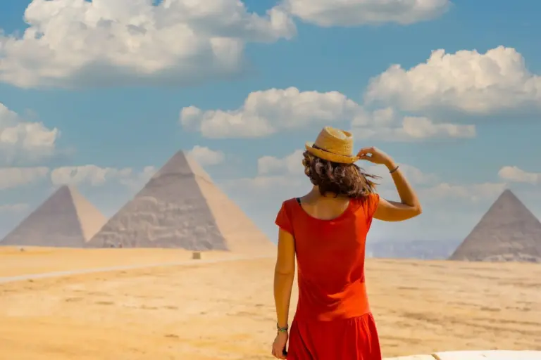 A young girl in a red dress at the pyramid of Cheops the largest pyramid at sunset