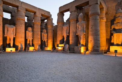 Illuminated ancient statues in temple ruins.