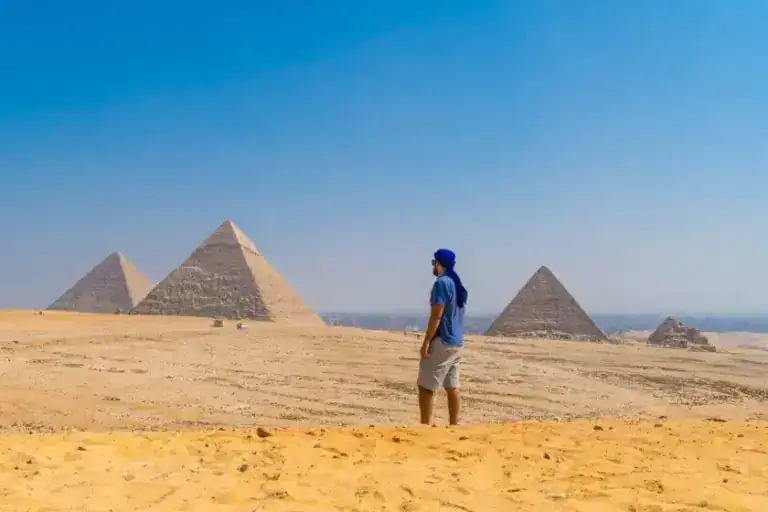 A Young Man In A Blue Turban Walking Next To The Pyramids Of Giza During A Discovery Tours Dmc Egypt Tour.