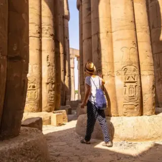 A young tourist in a white t-shirt and hat looking at ancient egyptian, Temple of Luxor, Egypt