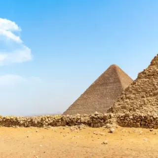 Three pyramids against a blue sky in desert.
