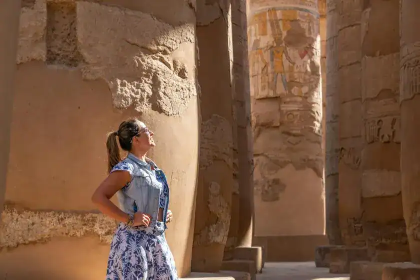 Woman in Luxor Temple admiring ancient carved columns in sunlight. Exclusive Itineraries by Discovery Tours Egypt Rich history of Egypt