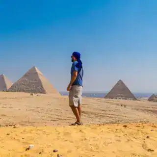 Portrait of a young man in a blue turban walking next to the Pyramids of Giza, Cairo, Egypt