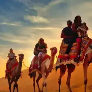 Tourists riding camels through the golden sand dunes of hurghada Desert Safari